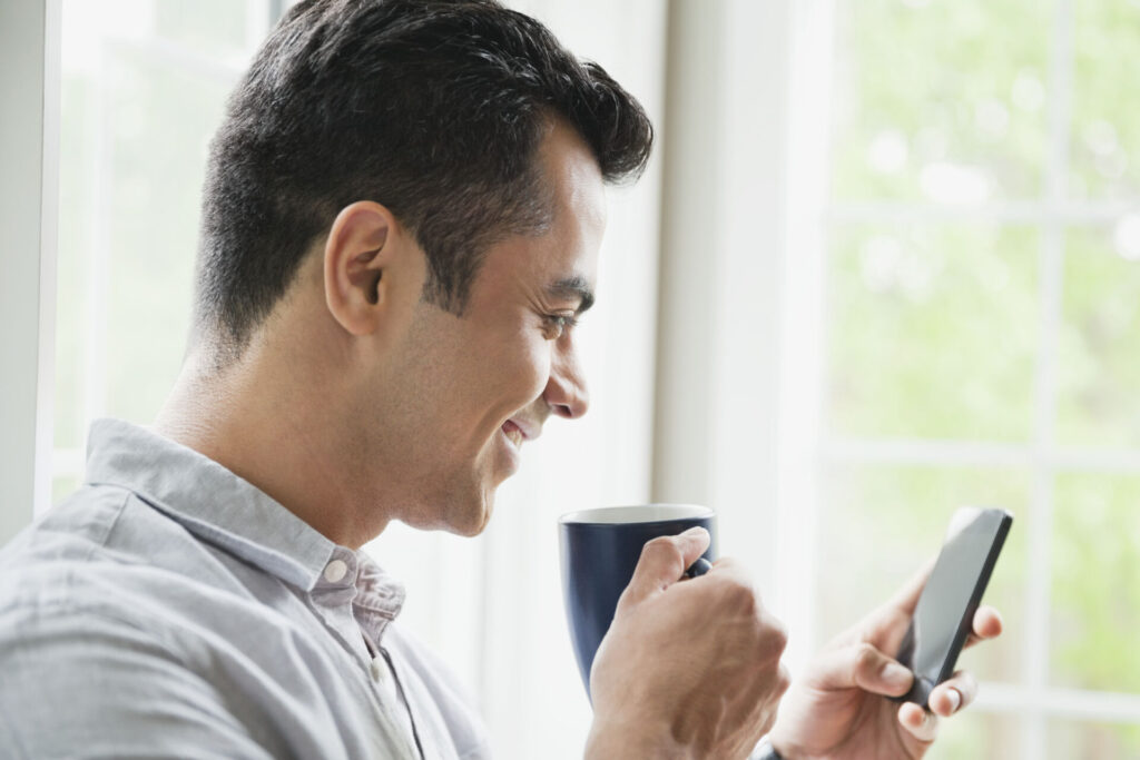 Man using smart phone while drinking coffee