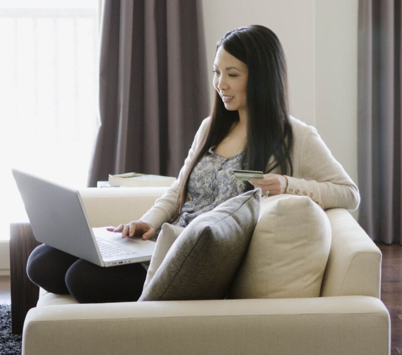 woman sitting on sofa using laptop